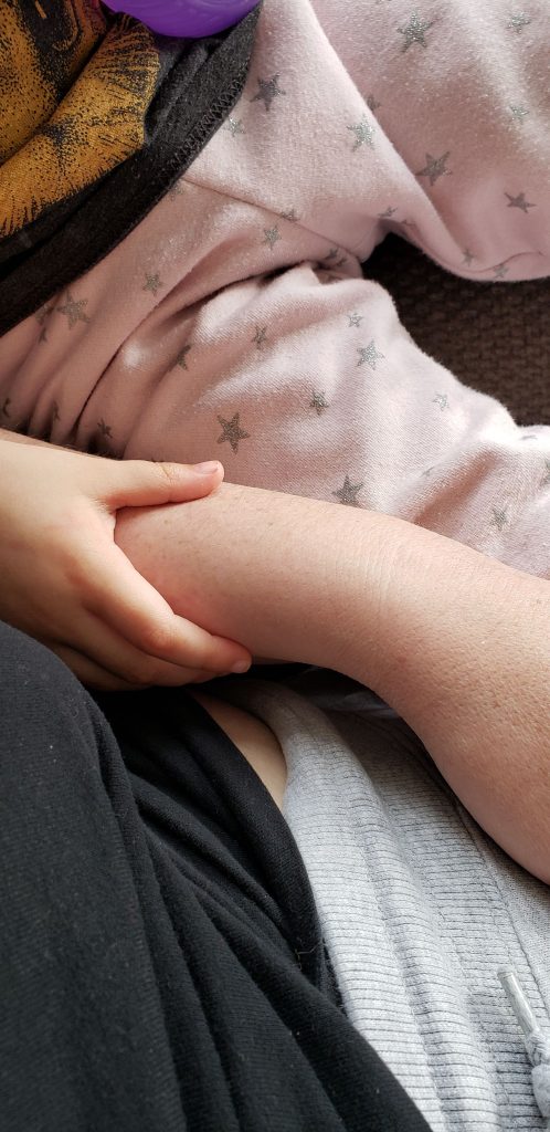 Toddler in pink sweatpants with stars with her hand on Arley's arm.