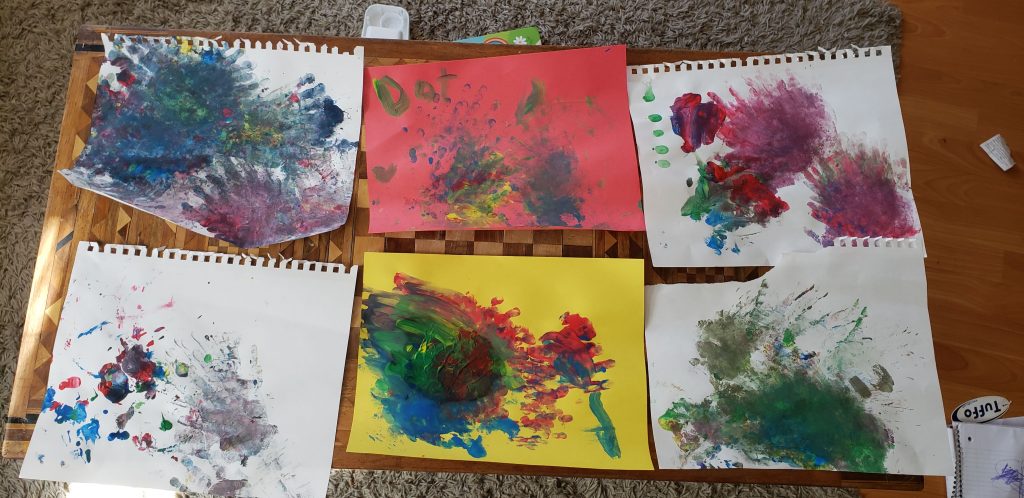 Six toddler drawings laid on a table.