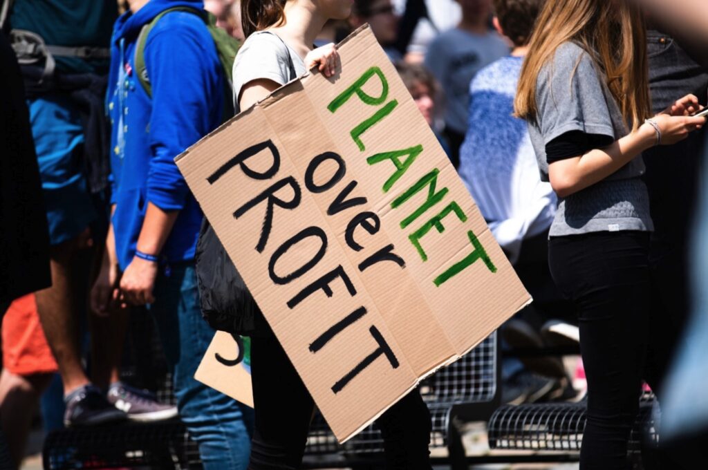 Protester holding a sign that reads "Planet over Profit"
